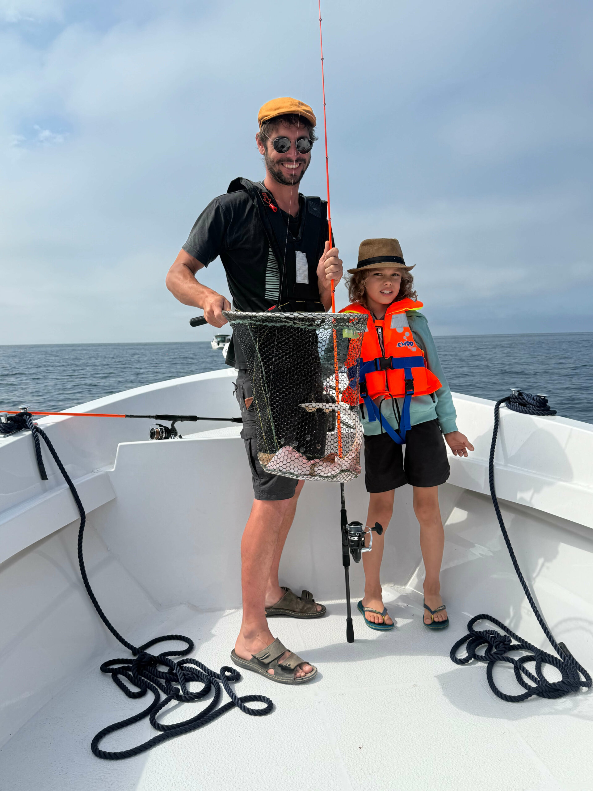 Enfant en gilet de sauvetage tenant un poisson à bord d’Aventure Pêche Camargue en Méditerranée